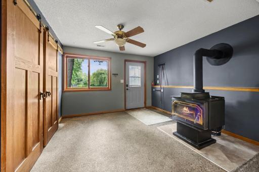 The walkout lower-level entry offers a practical, versatile space featuring a large closet for storage and a cozy woodstove. With its durable-looking flooring, this area is well-suited for dogs, hobbies, or creative projects.