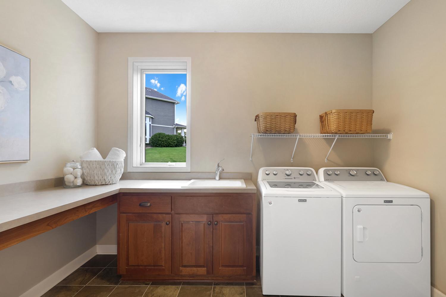 Spacious main-level laundry room with utility sink, abundant cabinetry, and folding counter.