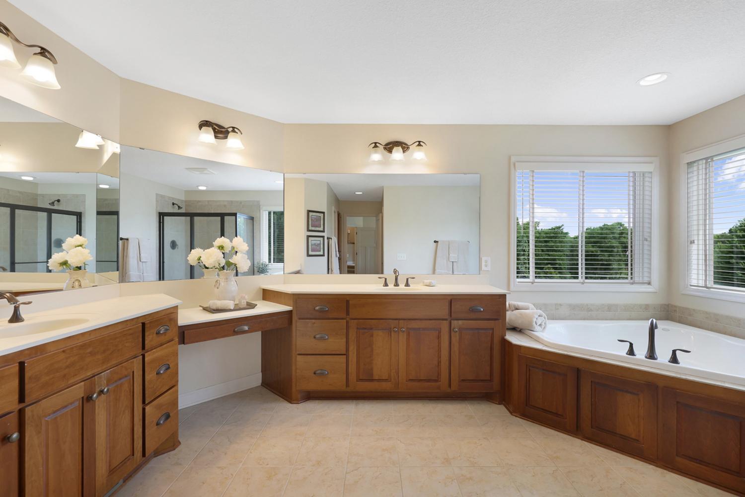 Spa-inspired primary bath featuring dual vanities, a relaxing jetted tub, and separate walk-in shower.