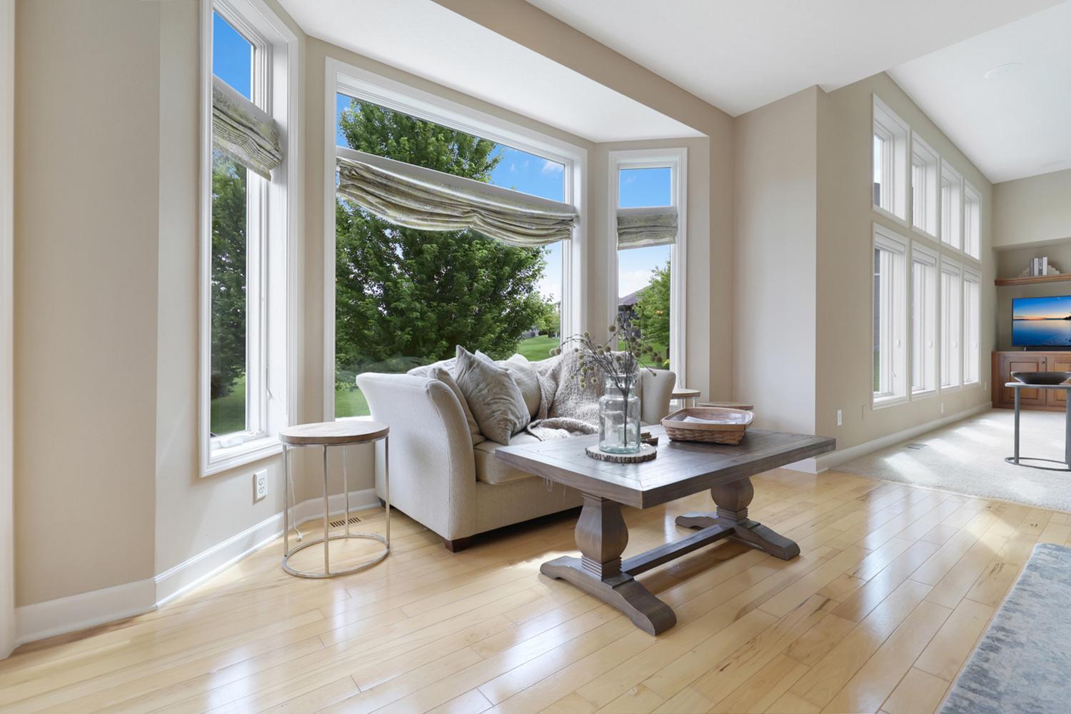 Sun-filled sitting area with walls of windows and scenic backyard views.