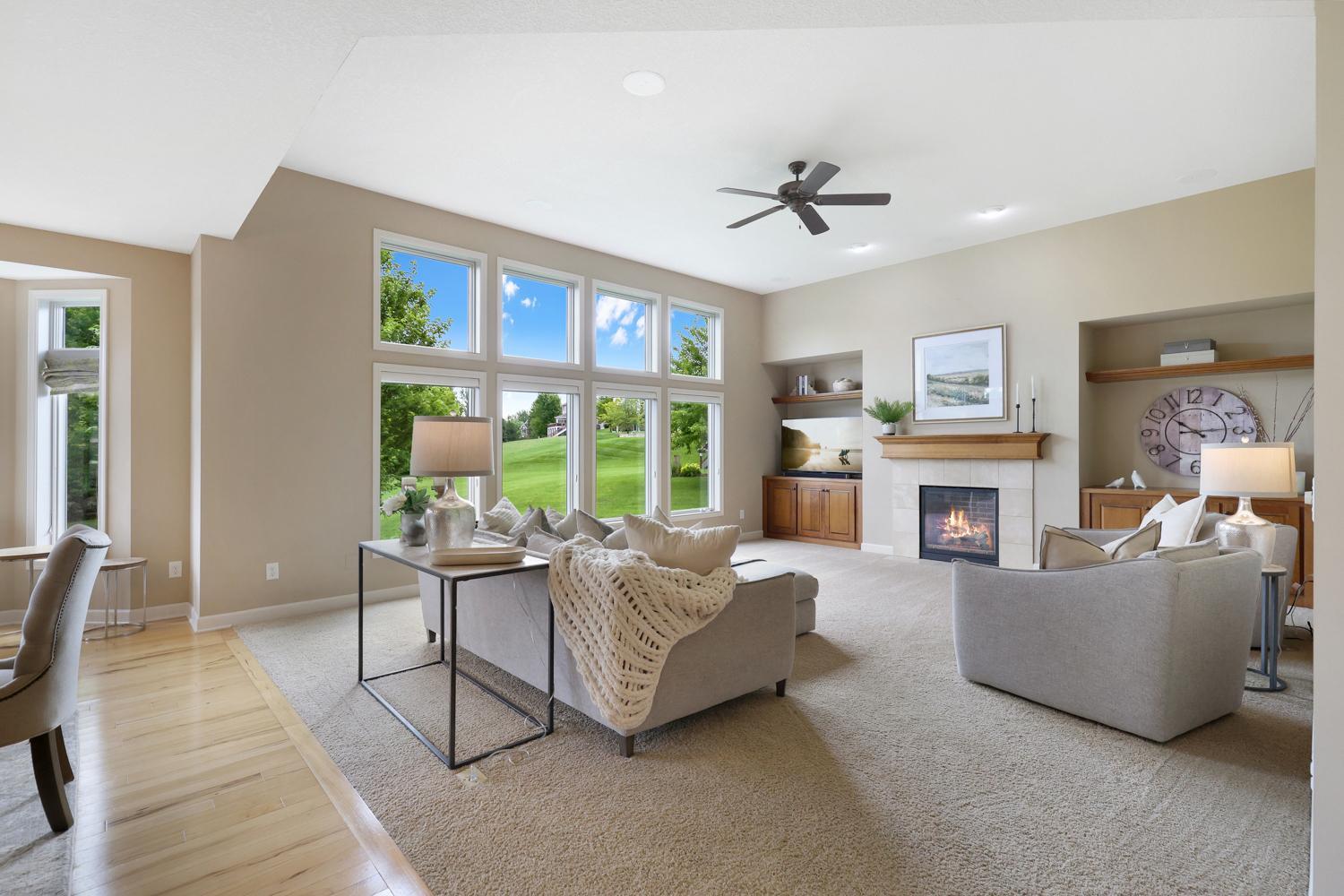Open concept great room highlighted by a gas fireplace, beautiful built-ins, and panoramic backyard views.