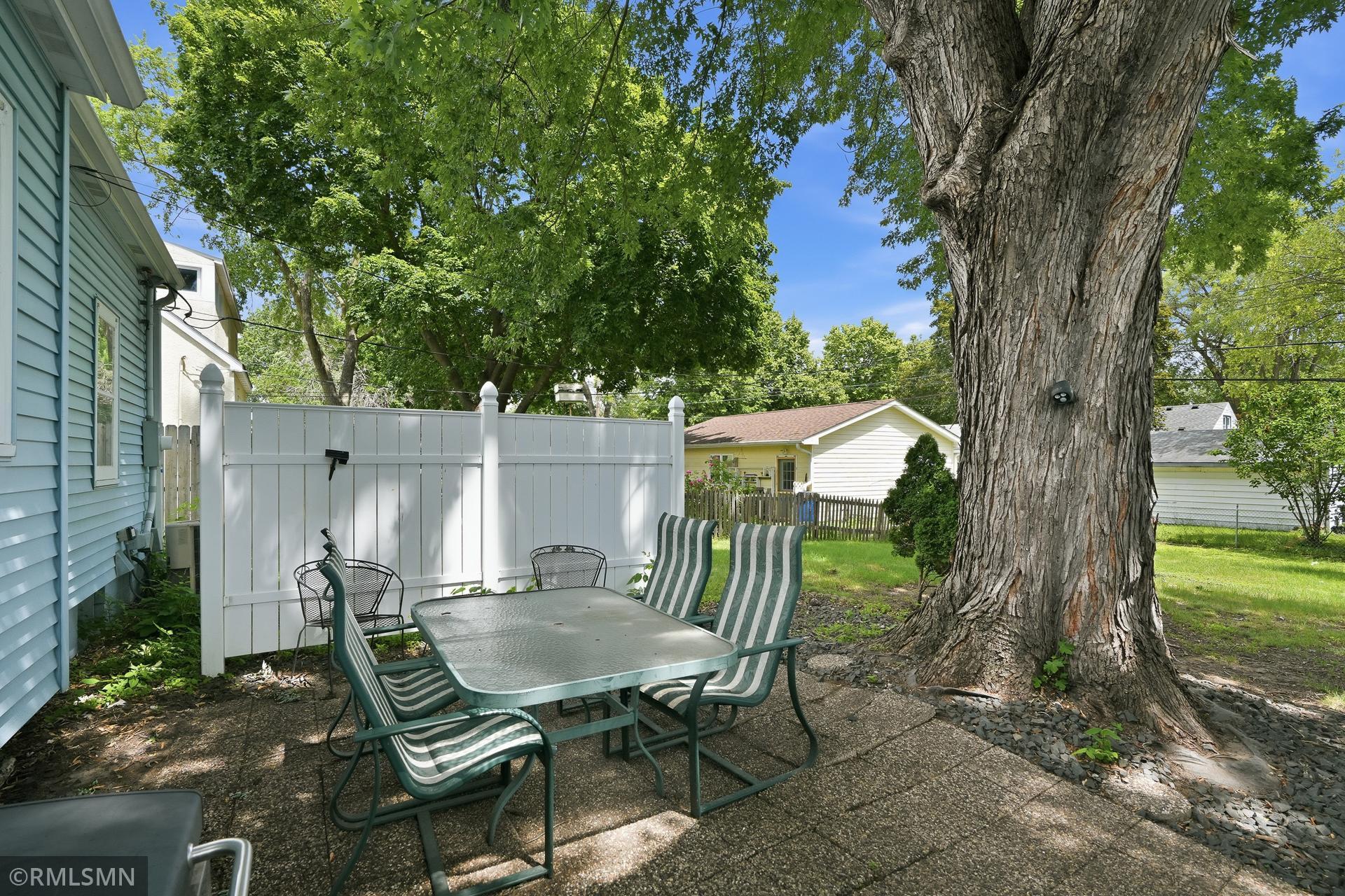 Fully fenced in yard, with patio under a shady tree along with a privacy wall