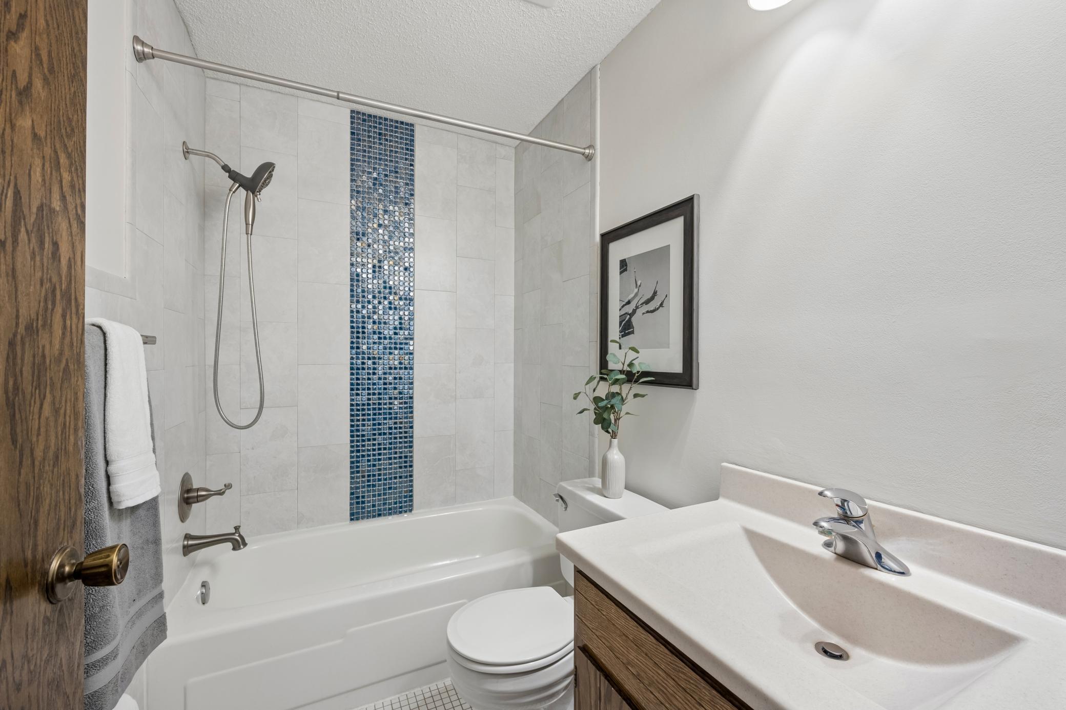 Main floor full bath featuring a beautifully tiled shower.