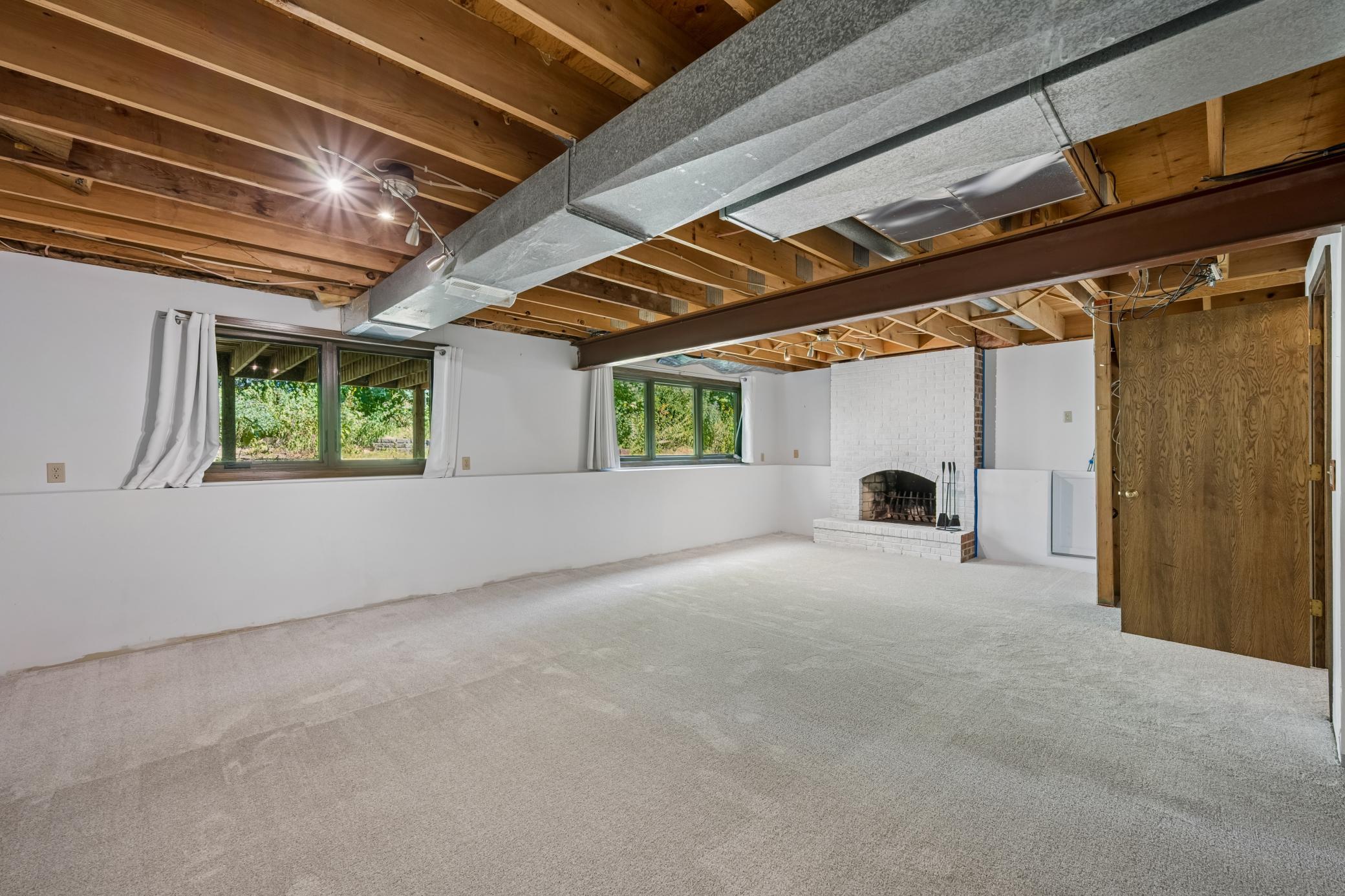 Unfinished lower level with new carpet, a fireplace, and plenty of potential for future living space.