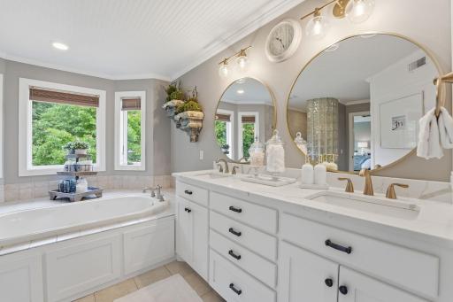 Dual vanity accented with gold and black finishes. Spa tub that has a large bay window.