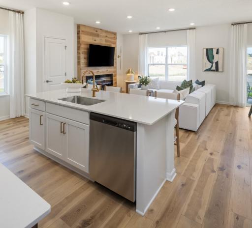 This Kitchen island flows seamlessly into a bright, inviting room, complete with a cozy fireplace and plenty of room to entertain. *Photo of a previously built home of the same floor plan. Finishes/options may vary.