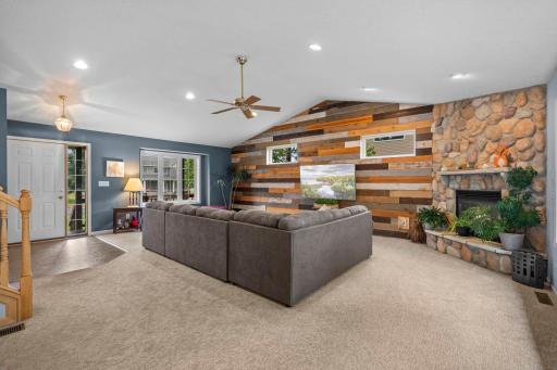 Spacious living room showcases soaring vaulted ceilings, a beautiful stone fireplace, and a barnwood feature wall that adds distinctive charm