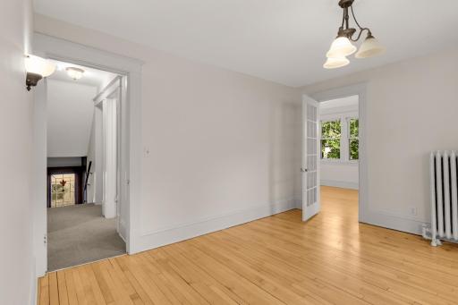 View of bedroom 1 with french door on right leading to the living room and door on left showing hallway to full bath and other bedrooms