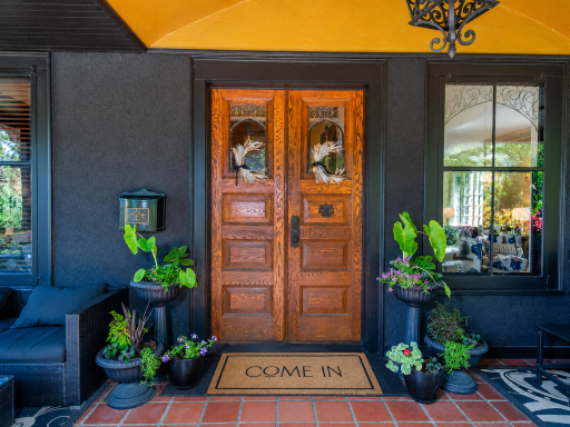 A welcoming covered entry showcases rich wood double doors with leaded glass, framed by a warm barrel-vaulted ceiling and classic wrought-iron lantern with terra cotta tile create a timeless an unmistakable first impression