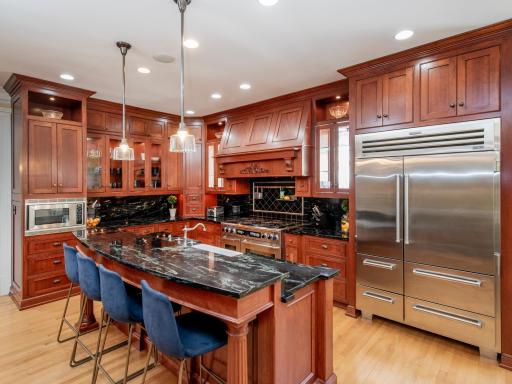 Floor-to-ceiling custom cabinetry illuminated by upper and under-cabinet lighting, features intricate storage solutions designed to beautifully organize every appliance and culinary essential