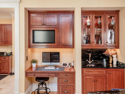 A well-appointed wet bar with additional glass cabinets and ice maker, and the workstation are practical and convenient