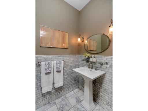 This adorable powder room with European marble tile and pedestal sink