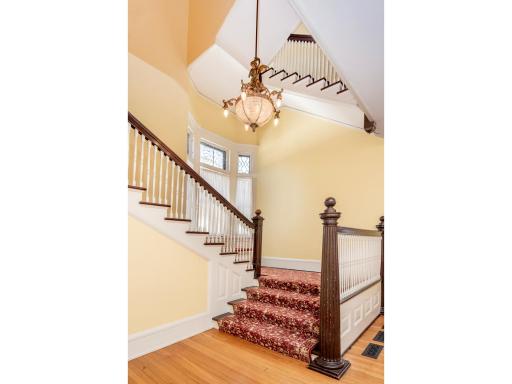 A breathtaking grand foyer sets the tone with a sweeping staircase, soaring ceilings, abundant natural light, and a charming bay window with a built-in window seat