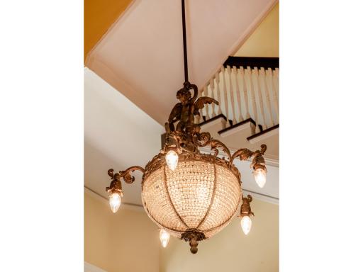 An elaborate crystal basket chandelier, accented with cherub figures and ornate bronze detailing, illuminates the foyer with Old World sophistication
