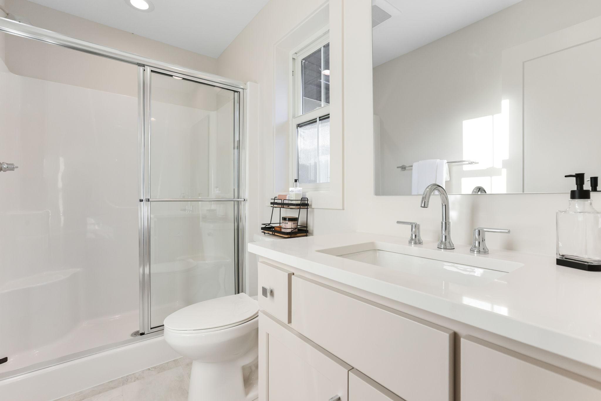 This private ¾ bathroom features a sleek quartz vanity, offering both style and functionality.