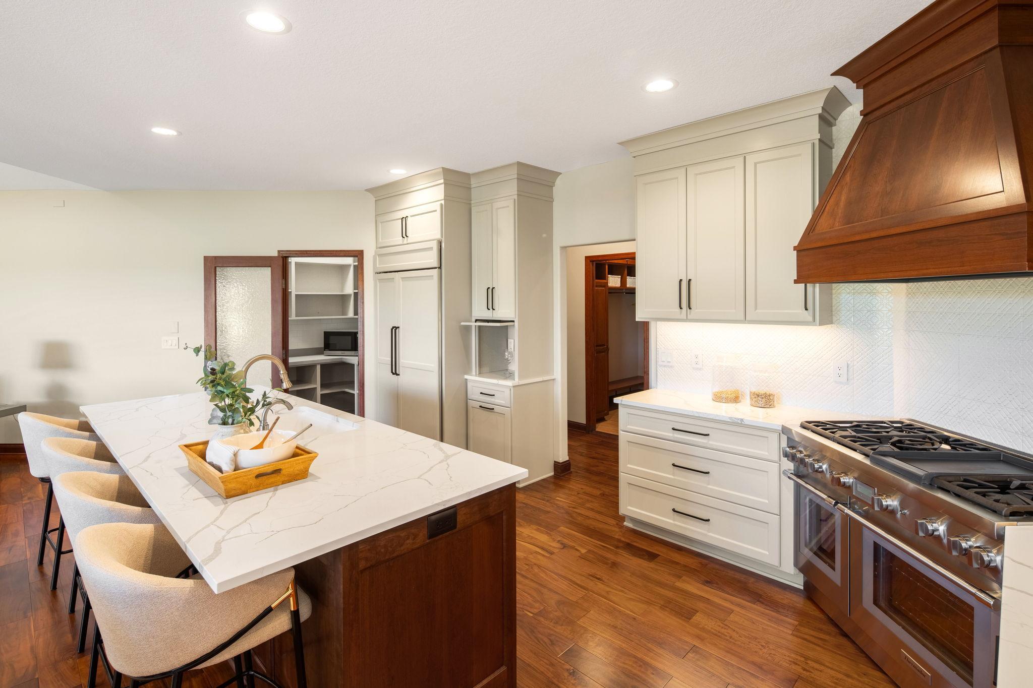 Detailed tile backsplash, soft-close cabinetry, under-cabinet lighting, and a walk-in pantry with custom organization and frosted glass door adds both function and style.