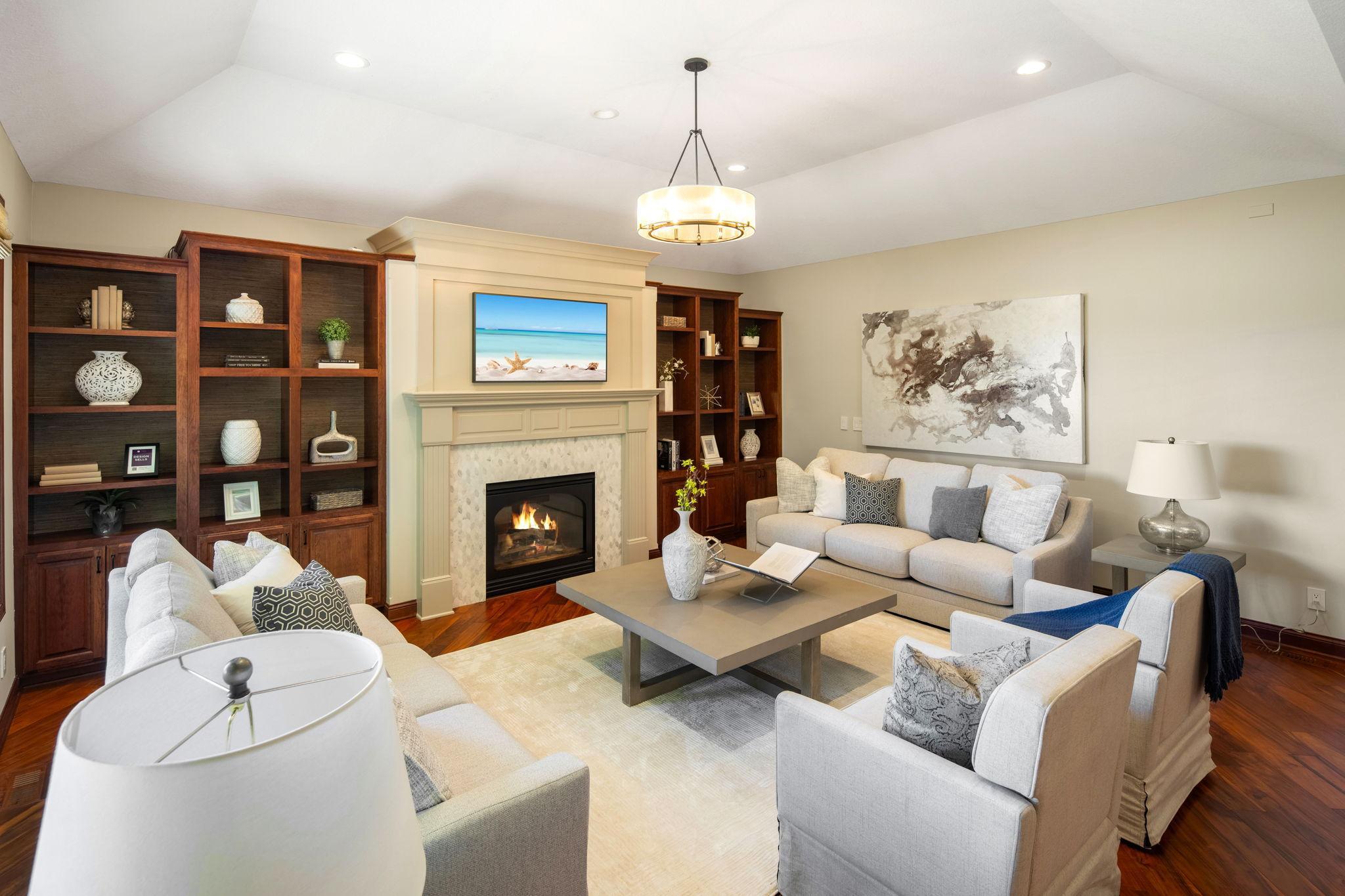 The living room features an 11-ft ceiling, gas fireplace with tile surround, framed by a full wall of built-ins, offering a warm and inviting focal point.