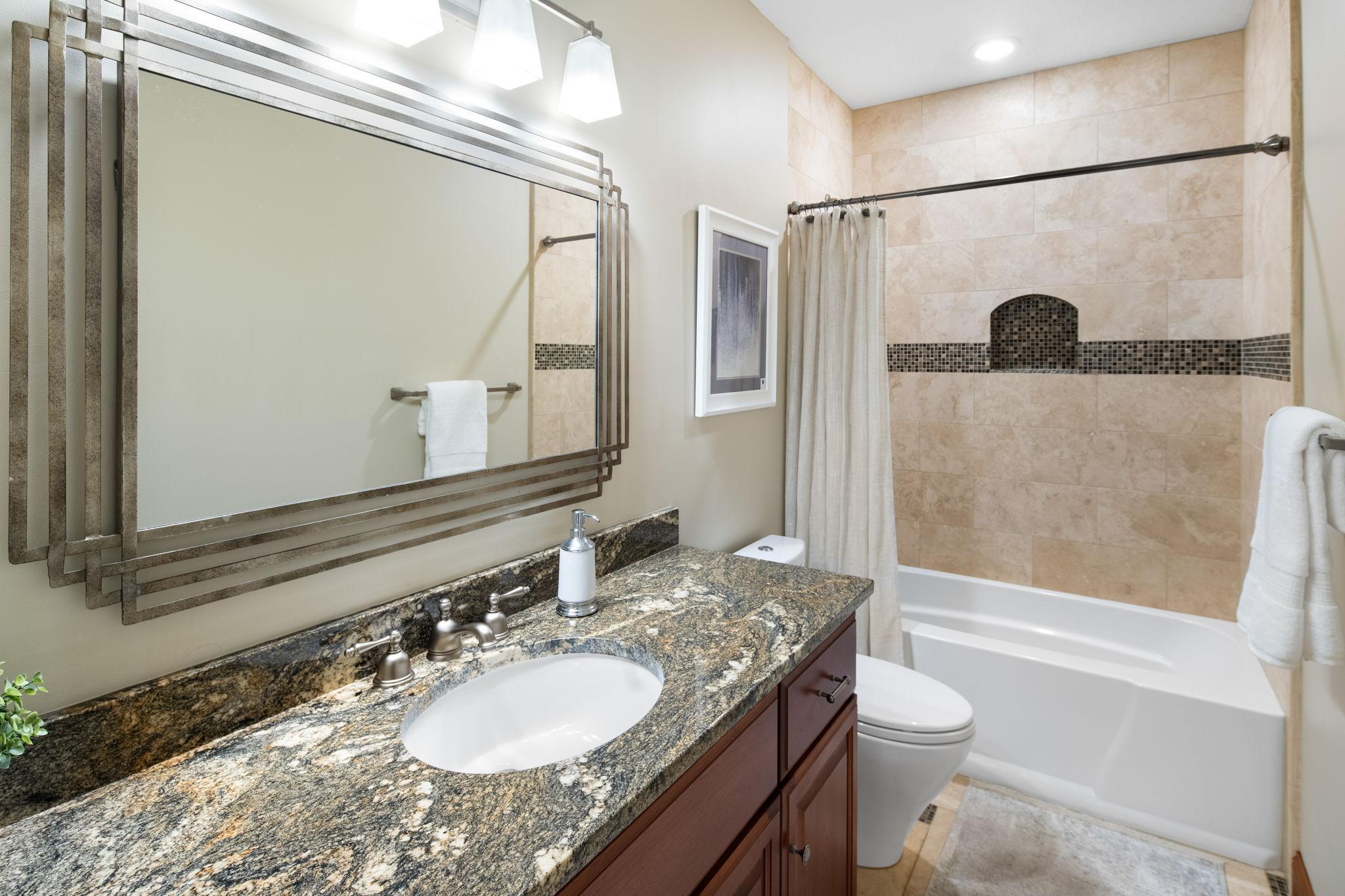 Lower level full bath with tiled tub/shower adds convenience.