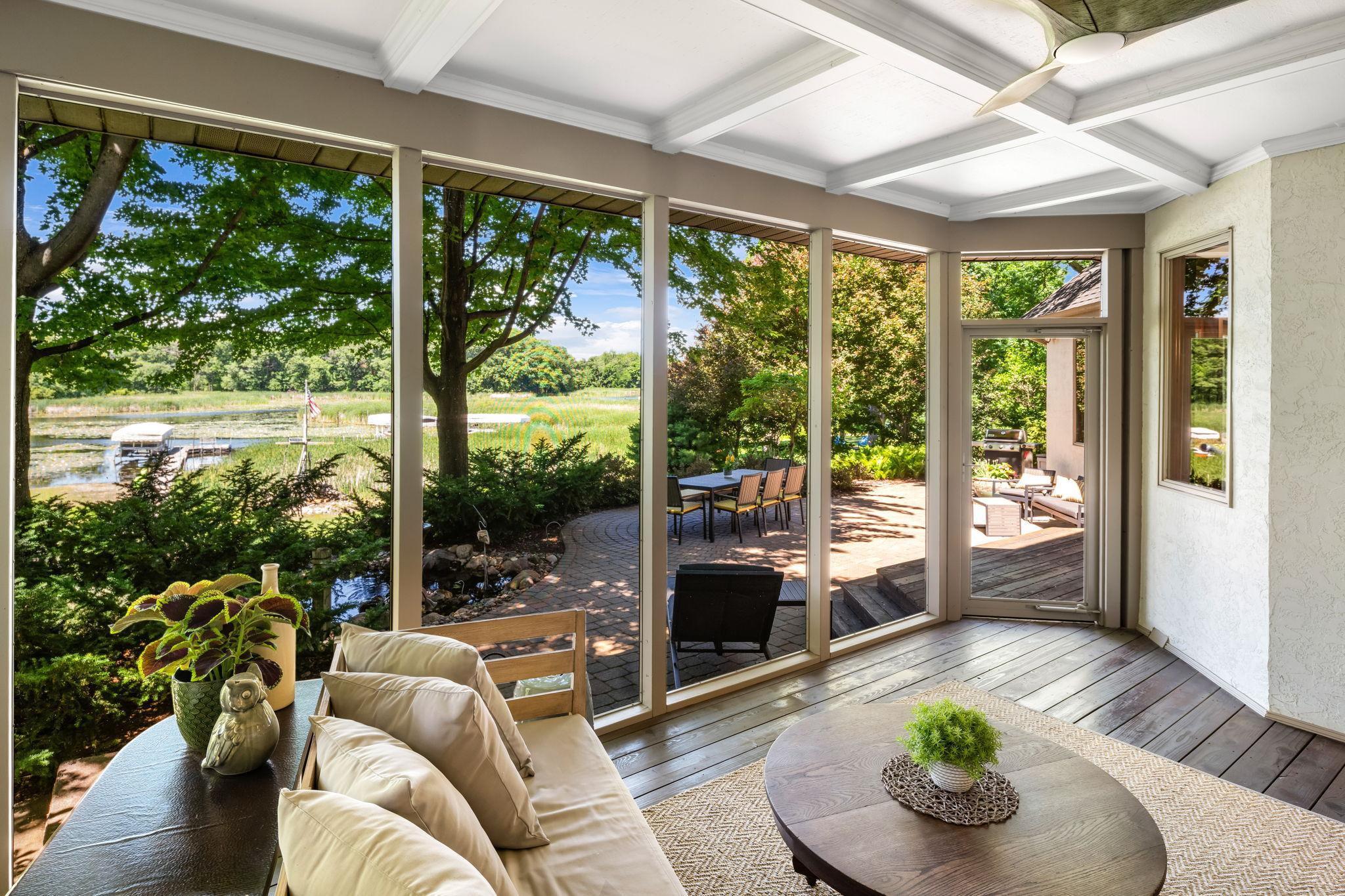 Just beyond, a screened porch extends the living area outdoors with peaceful views of nature, ceiling fan comfort, and built-in speakers.