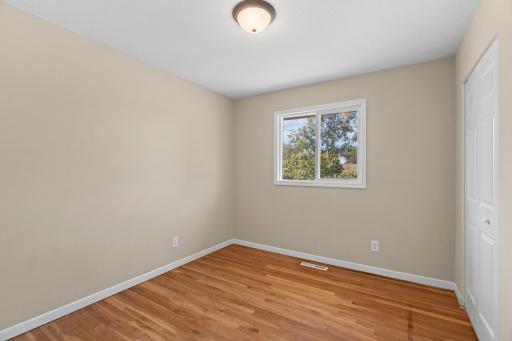 Versatile bedroom or flex space at 16860 Foliage Ave W with wood-look plank flooring, neutral beige walls, white trim, and a picture window providing natural daylight.