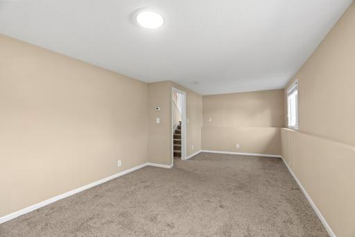 Open, sunlit lower-level living area at 16860 Foliage Ave W with neutral wall-to-wall carpeting, flush-mount lighting, garden-level windows, and ample space for an entertainment center, workout studio, or play area.