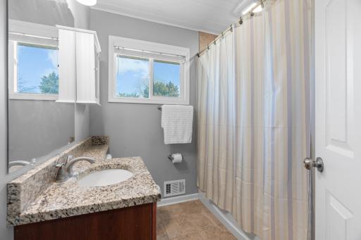 Updated bathroom at 16860 Foliage Ave W featuring a speckled solid-surface vanity countertop, undermount sink, soft grey walls, privacy window, and a full shower/tub combination.