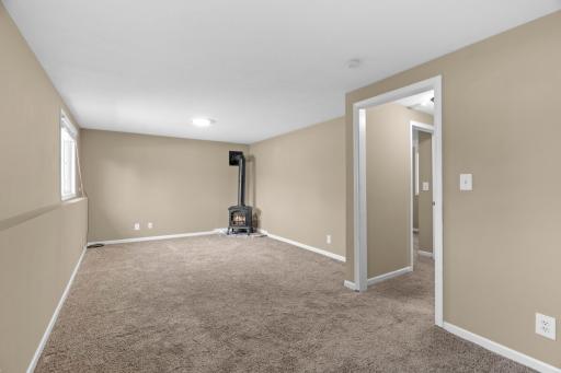 Expansive finished lower-level family recreation room at 16860 Foliage Ave W featuring plush neutral carpeting, a freestanding stove/fireplace, recessed lighting, and direct access to adjacent flex rooms.