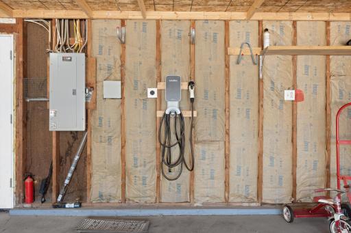 Attached garage utility wall at 16860 Foliage Ave W equipped with a dedicated Level 2 electric vehicle (EV) charging station and insulated framing ready for finishing.