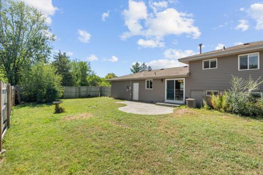 Spacious, flat backyard at 16860 Foliage Ave W featuring an expansive green lawn, concrete patio pad off the walkout sliding glass door, and perimeter privacy fencing.