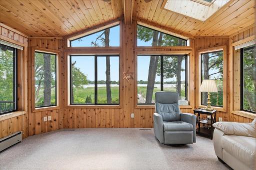 Four Season Porch with vaulted ceiling w/skylights, ceiling fan/light and knotty pine walls. Beautiful panoramic lake views from the walls of windows