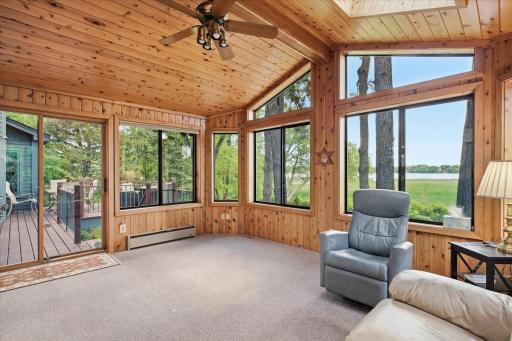 Gorgeous Sunroom features panoramic lake views, walls of windows, knotty pine walls/ceiling, skylights and slider to the deck