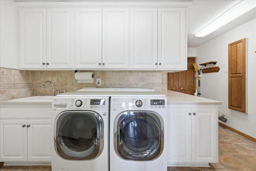 Convenient expanded Laundry/Mudroom w/LG washer/dryer, LVT flooring, custom white cabinets, large wet sink and lots of counter space and closet