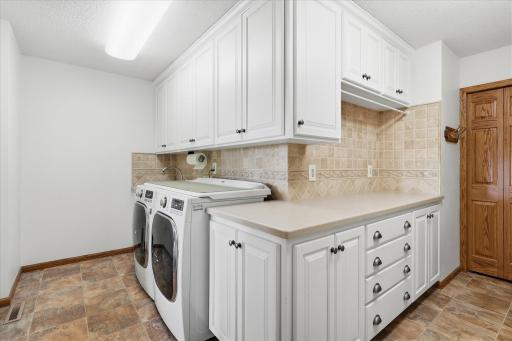 Convenient expanded Laundry/Mudroom w/LG washer/dryer, LVT flooring, custom white cabinets, large wet sink and lots of counter space and closet