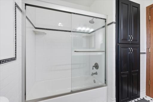 Remodeled Upper Level Full Bathroom features: Quartz counter top vanity, half tile walls + flooring, glass shower doors and linen closet