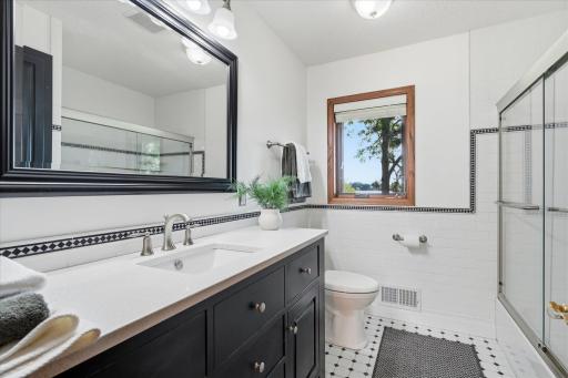 Remodeled Upper Level Full Bathroom features: Quartz counter top vanity, half tile walls + flooring, glass shower doors and linen closet