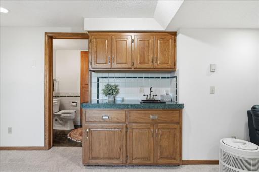 Lower level Amusement wet bar with granite counter top, tile backsplash and built-in cabinets