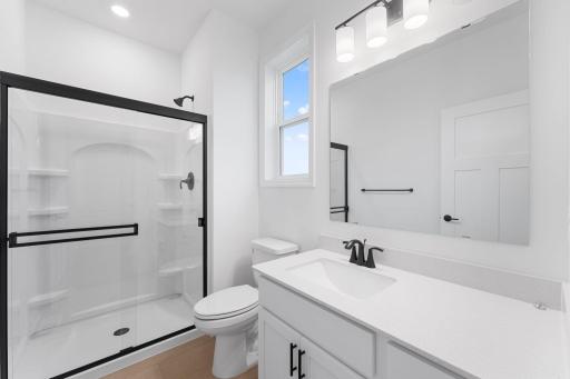 This bathroom is discreetly located down a hallway off the foyer, offering access to a single vanity and glass-enclosed shower.