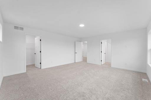 The primary bedroom embraces natural light streaming in from the large windows