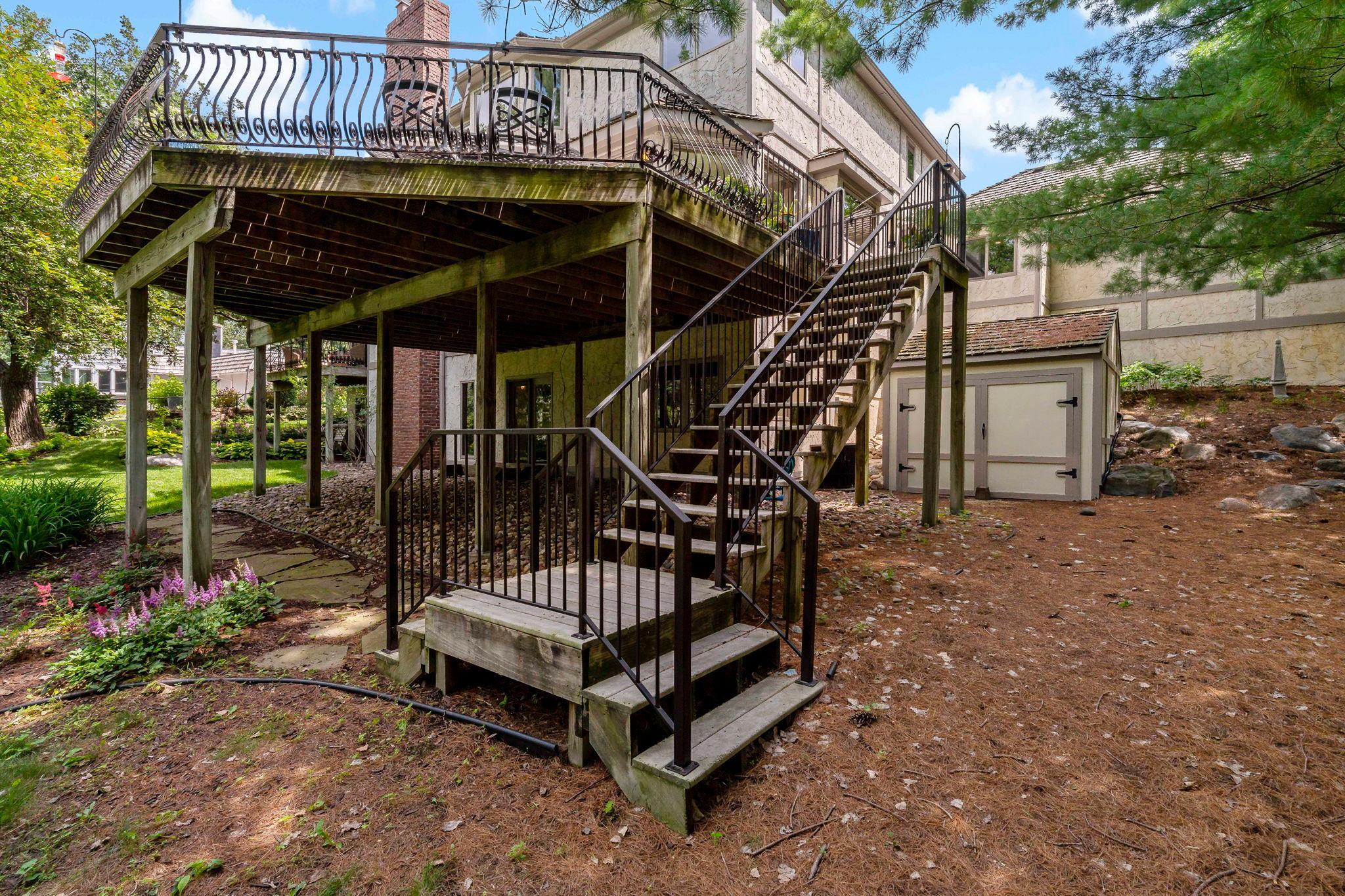 Steps off the deck lead to backyard, which includes storage shed