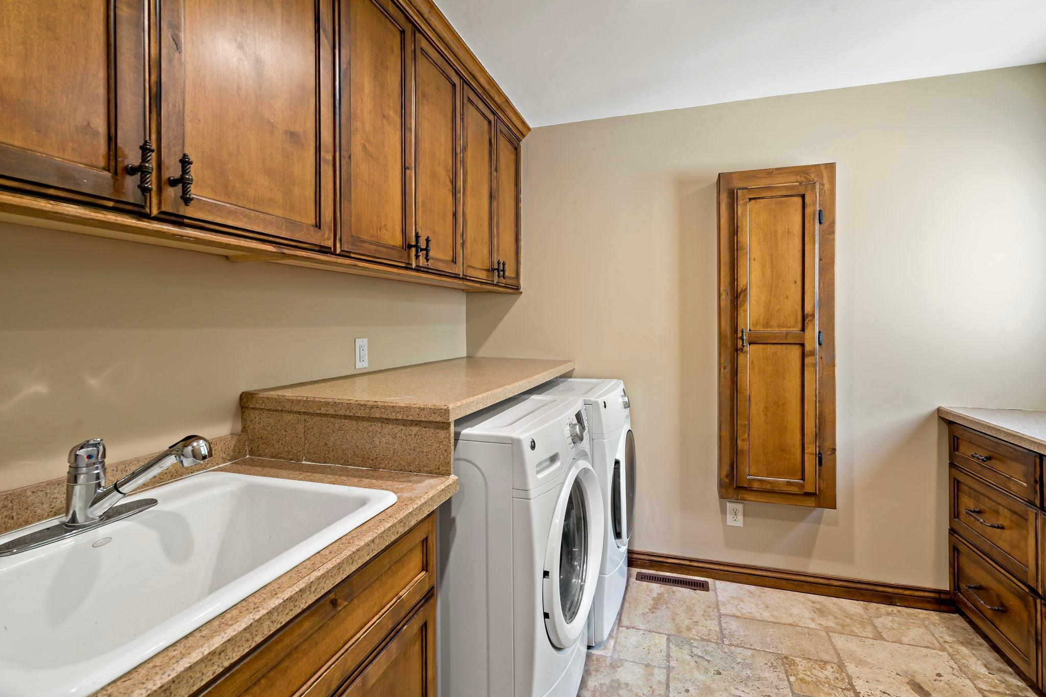 Main floor laundry room with sink and ample storage, just steps from the three car garage