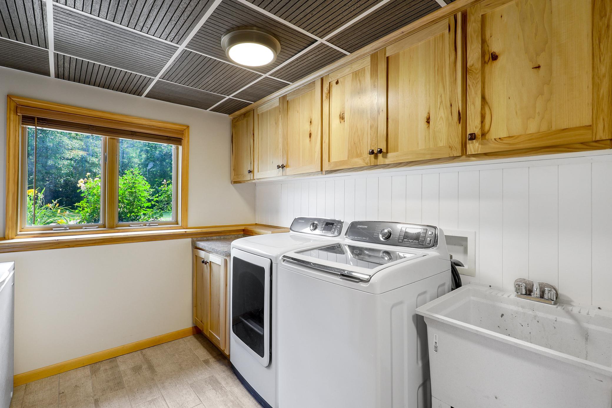 The laundry space is beautifully updated with hickory cabinetry, Samsung appliances, an improved drop ceiling, and wainscoting.