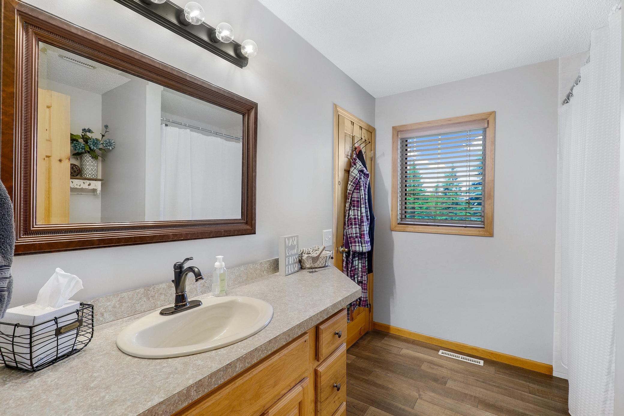 The main level primary bedroom offers vaulted ceilings, peaceful nature views, a wide double door closet, and direct access to the walk-through bathroom, while a second generously sized bedroom features its own walk in closet.