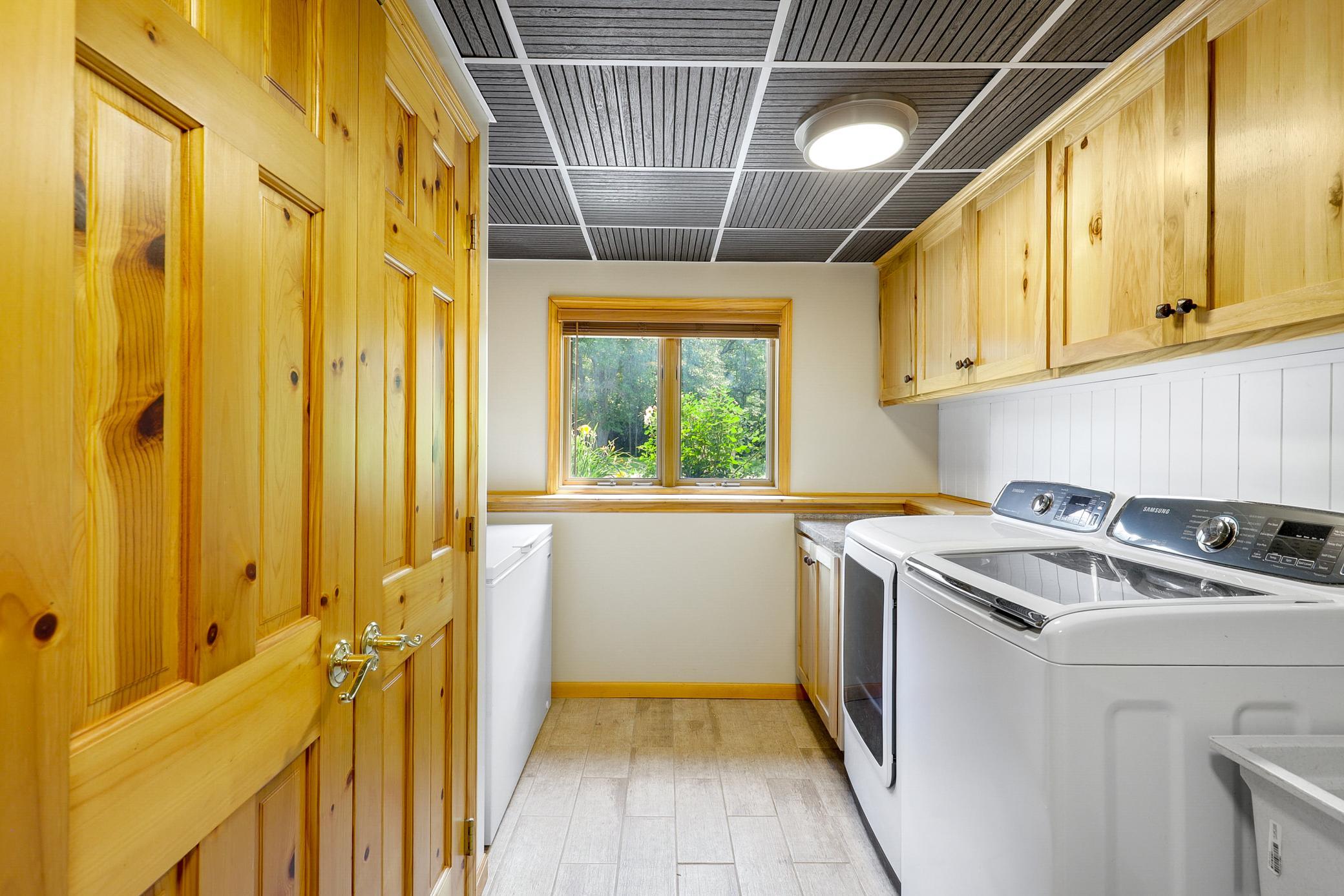The laundry space is beautifully updated with hickory cabinetry, Samsung appliances, an improved drop ceiling, and wainscoting.