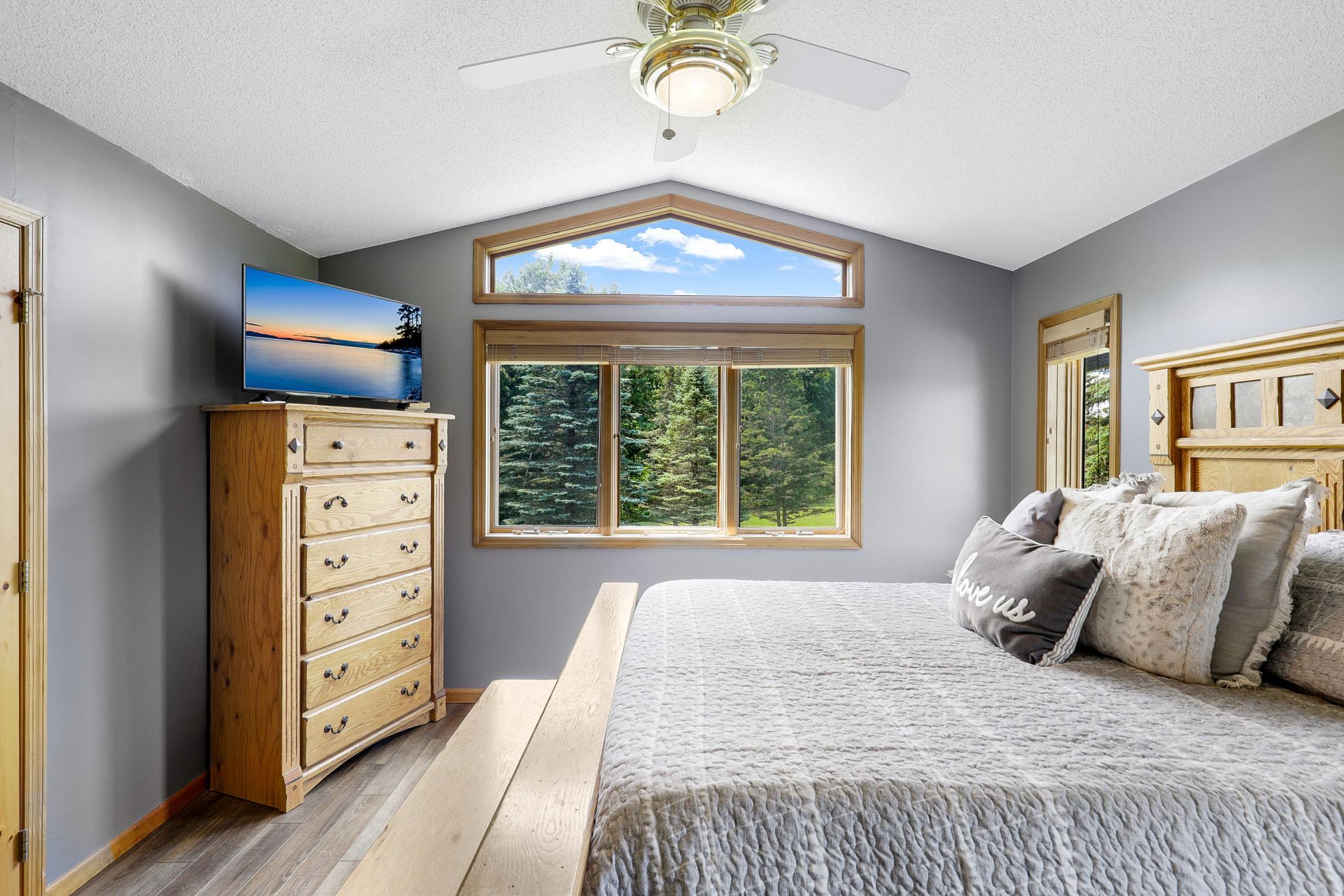 The main level primary bedroom offers vaulted ceilings, peaceful nature views, a wide double door closet, and direct access to the walk-through bathroom, while a second generously sized bedroom features its own walk in closet.