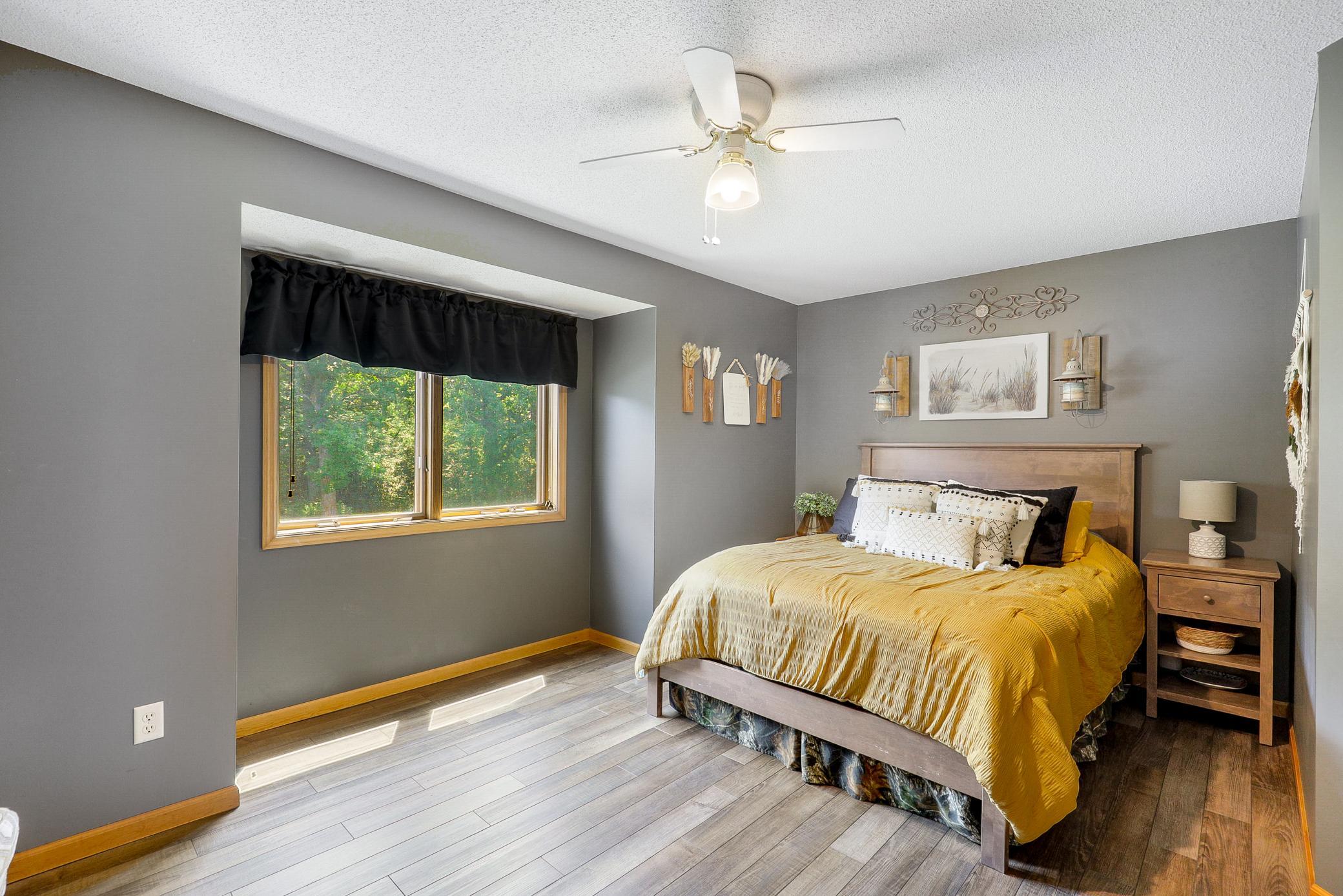 The main level primary bedroom offers vaulted ceilings, peaceful nature views, a wide double door closet, and direct access to the walk-through bathroom, while a second generously sized bedroom features its own walk in closet.