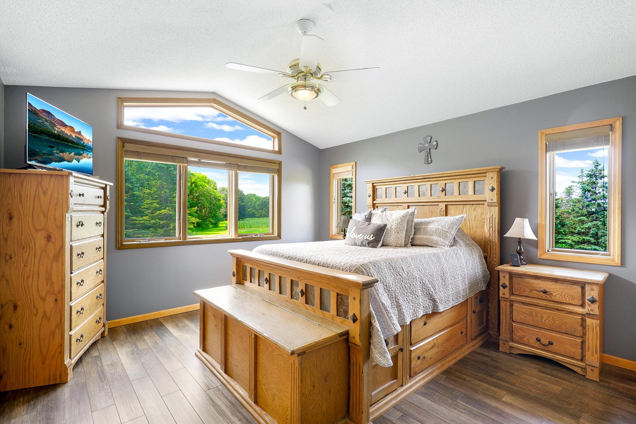 The main level primary bedroom offers vaulted ceilings, peaceful nature views, a wide double door closet, and direct access to the walk-through bathroom, while a second generously sized bedroom features its own walk in closet.