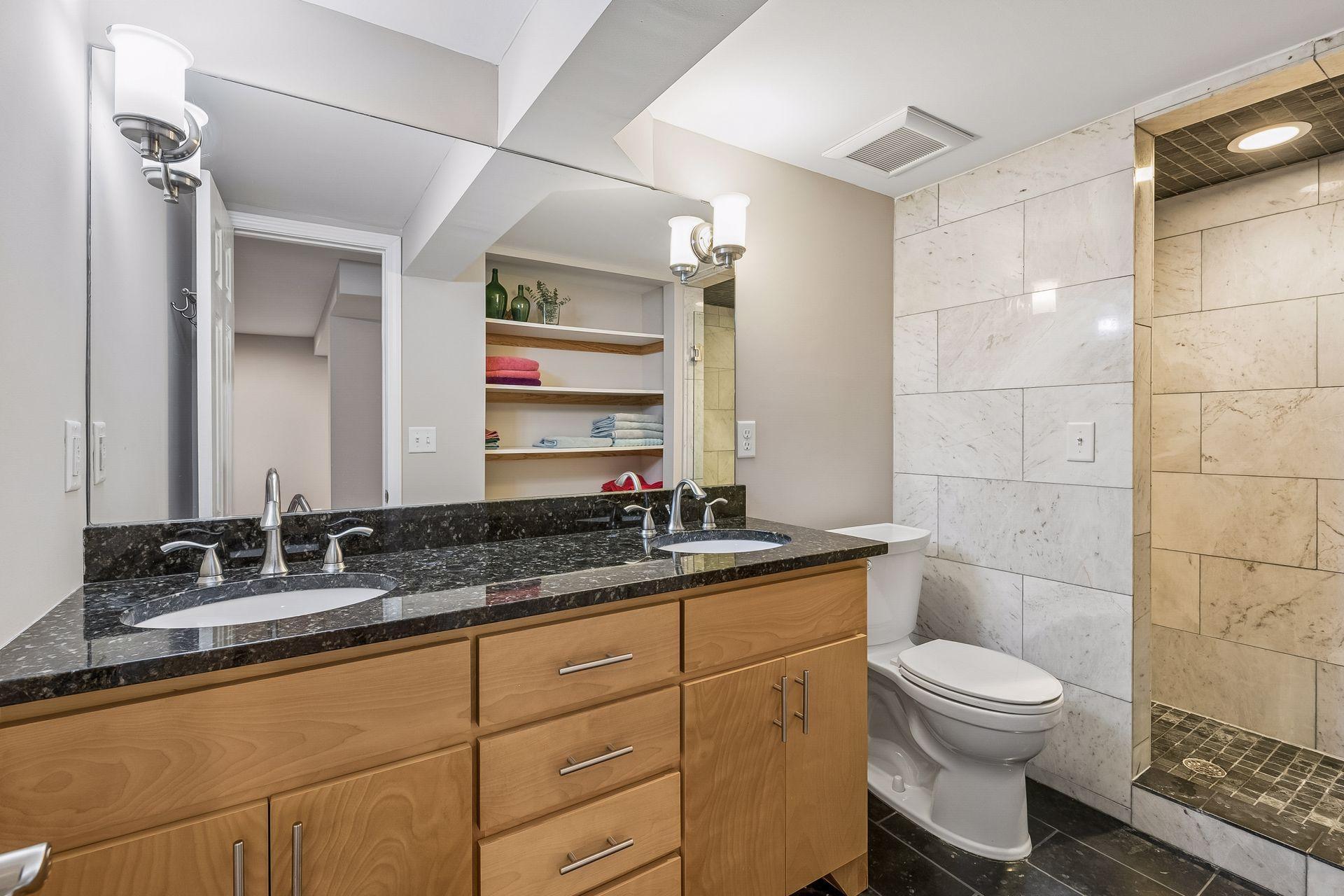 3/4 bath in lower level with walk-in shower, granite counters and double sinks