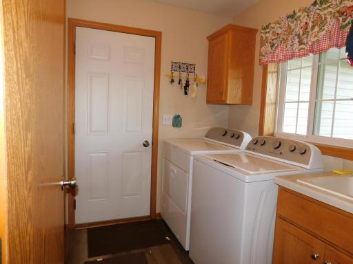 Main floor laundry with washtub by garage with closet and storage.