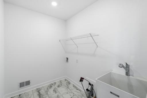 The laundry room will simplify chore days with an overhead shelf and washer-dryer connections.