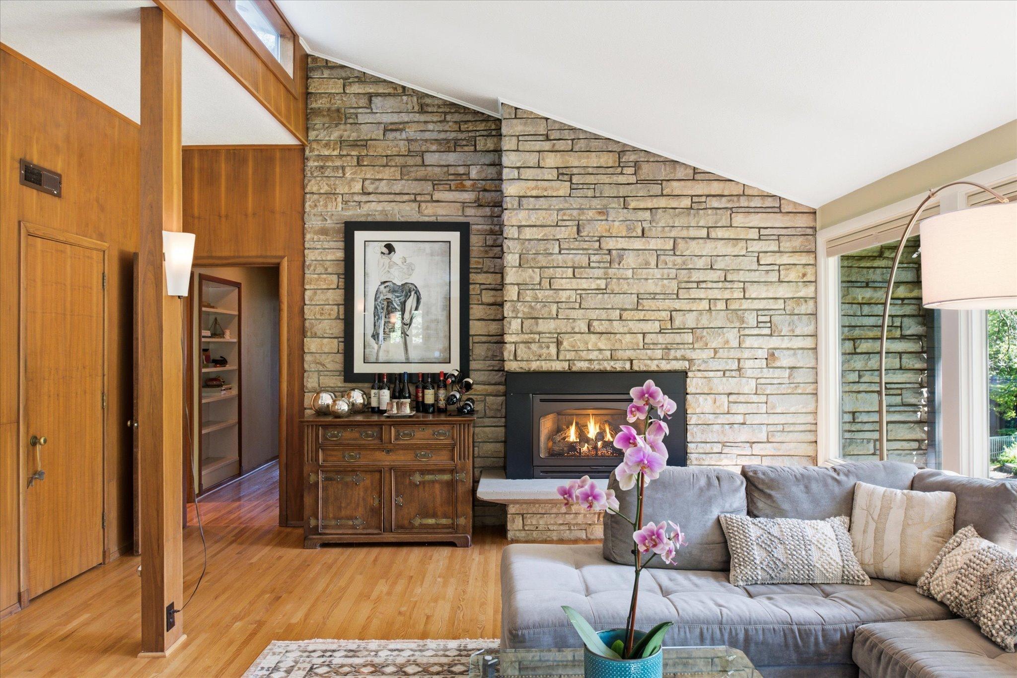 Gas fireplace showcased by stone floor to ceiling wall